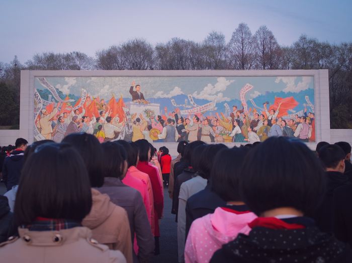 Women in front of a mural in North Korea.